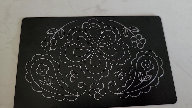 Business sized metal blank with one of the free Scan N Cut foil designs engraved onto it using the Zoom tool.