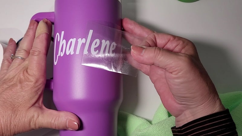Peeling the transfer tape from the project revealing the personalized name on the mug
